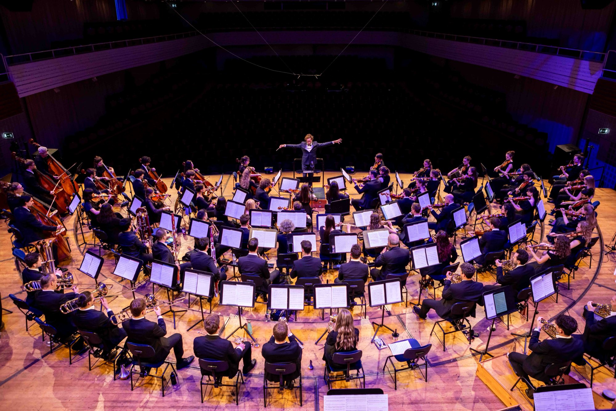 Orchestra on stage seen from above, conductor in the middle